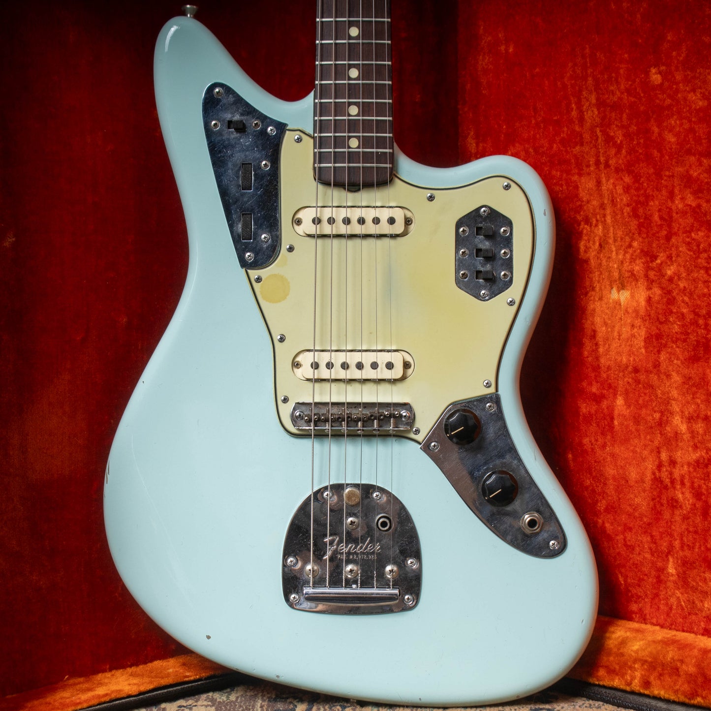 Light blue electric guitar with Fender logo on a red background